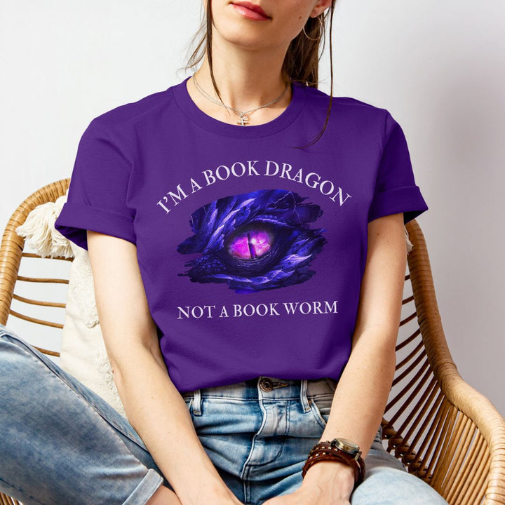 A woman wearing a short sleeve purple t-shirt. Design on the shirt reads "I'm a book dragon not a book worm." Between the text is the purple dragon eye from the cover of Stormsight.