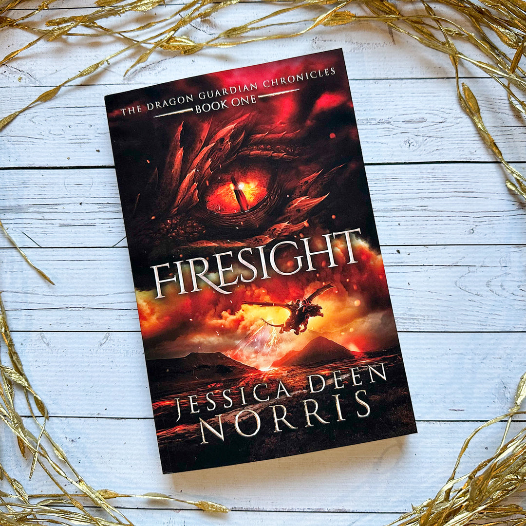 Firesight paperback cover. Cover features the title across the middle with a red dragon eye and "The Dragon Guardian Chronicles Book 1" above it. Below the title, the two main characters ride on a dragon over a volcano erupting. The author's name is at the bottom of the cover.#autograph-option_unsigned