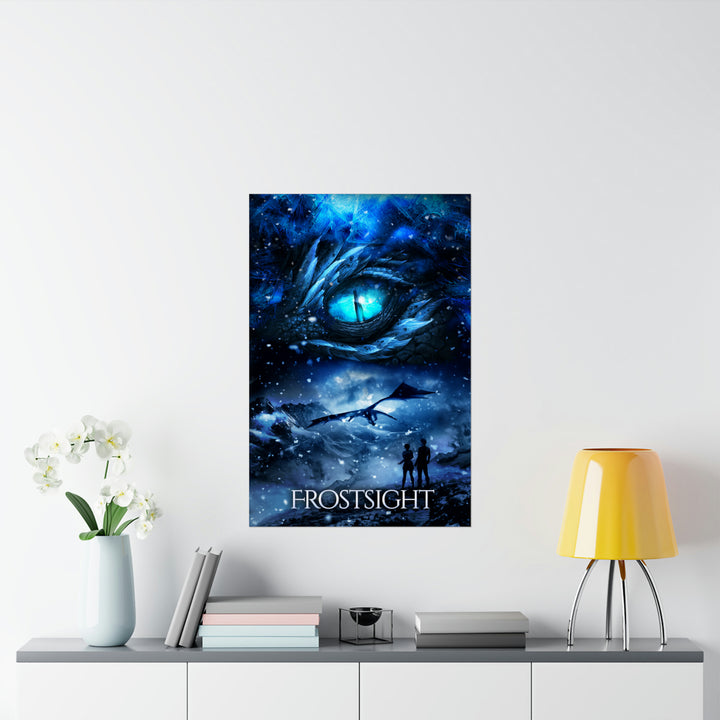 A poster hanging on a wall featuring the artwork from the cover of Frostsight. Artwork features a blue dragon eye at the top. Below the eye, the two main characters watch a dragon in the distance in a snowy mountain landscape. The title is at the bottom of the poster.