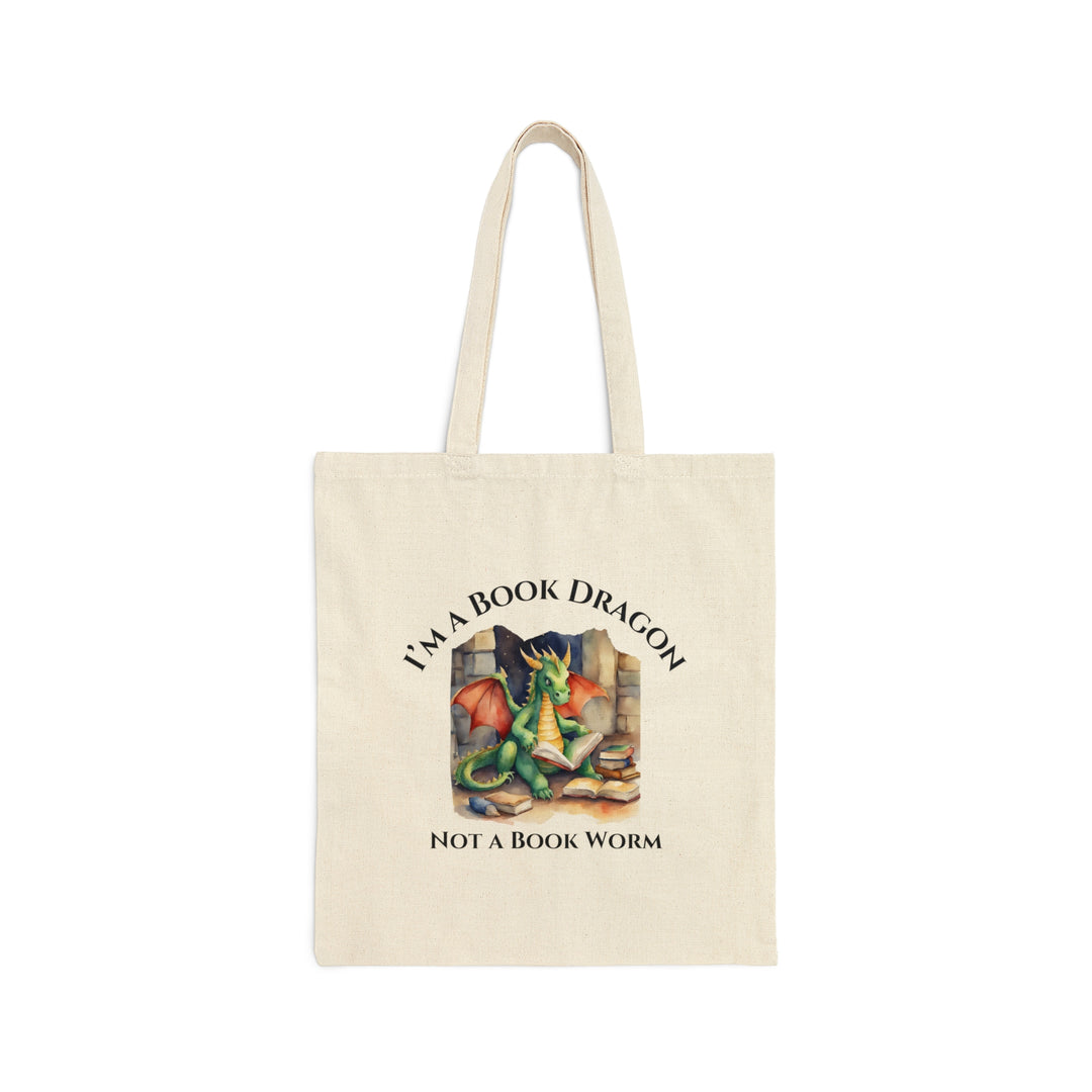 A tan canvas tote bag. Design on the tote bag reads "I'm a book dragon not a book worm." Between the text is a watercolor design of a dragon reading next to a stack of books.