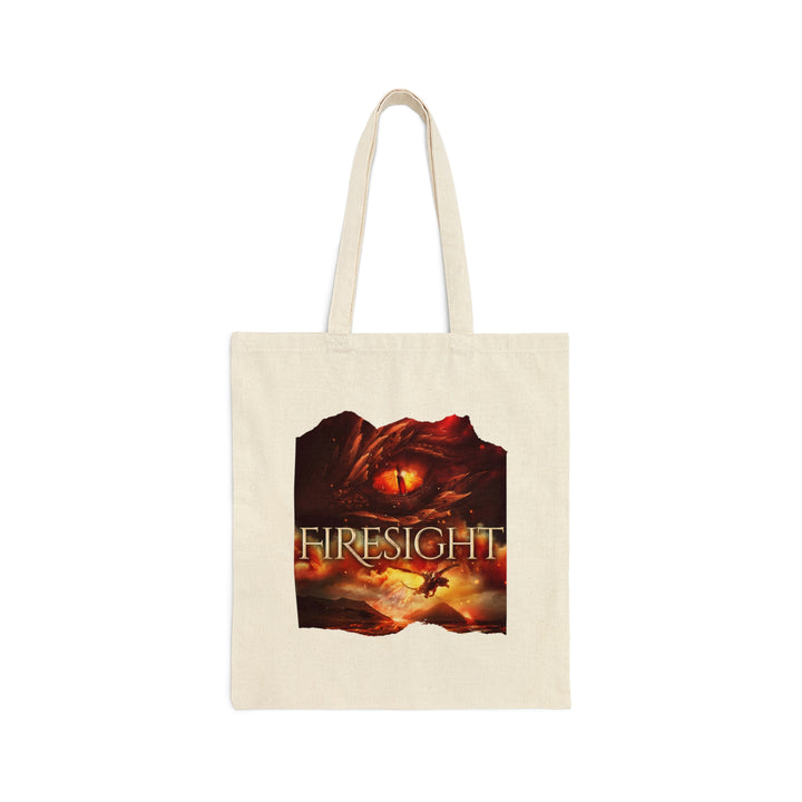 A tan canvas tote bag. Design on the tote bag is the cover of Firesight, just showing the red dragon eye and the title with the two main characters riding on a dragon over a volcano erupting.
