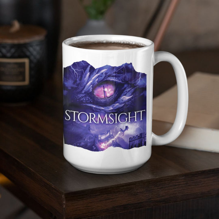 A white mug on a table. Design on the mug is the cover of Stormsight, just showing the purple dragon eye and the title with the a dragon breathing lightning onto a wall.