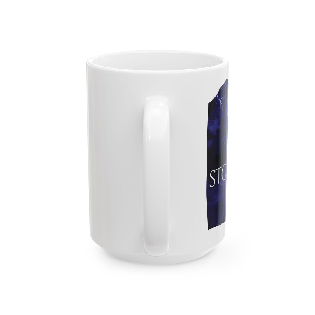 A white mug on a table. Design on the mug is the cover of Stormsight, just showing the purple dragon eye and the title with the a dragon breathing lightning onto a wall.