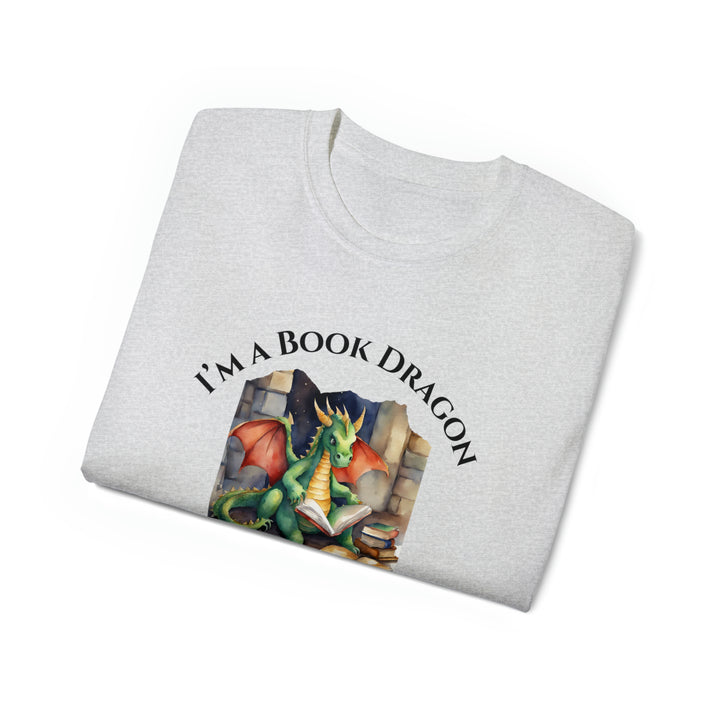 A folded heather gray t-shirt. Design on the shirt reads "I'm a book dragon not a book worm." Between the text is a watercolor design of a dragon reading next to a stack of books.