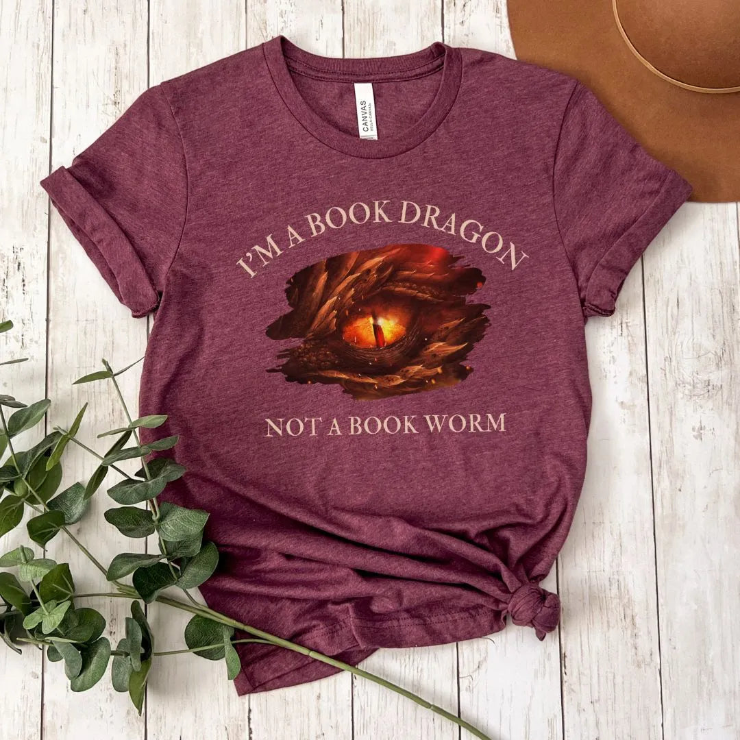 A short sleeve heather maroon t-shirt. Design on the shirt reads "I'm a book dragon not a book worm." Between the text is the red dragon eye from the cover of Firesight.