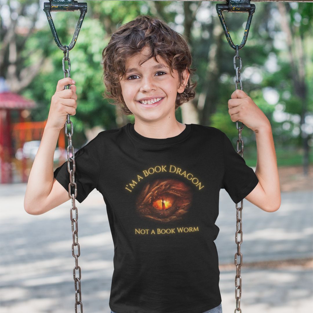 A young boy wearing a short sleeve black t-shirt. Design on the shirt reads "I'm a book dragon not a book worm." Between the text is the red dragon eye from the cover of Firesight.