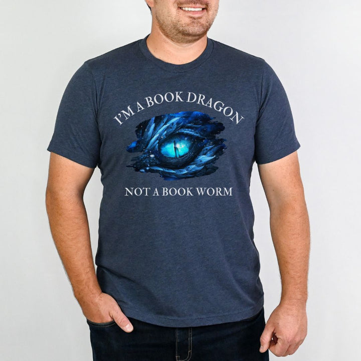 A man wearing a short sleeve heather navy t-shirt. Design on the shirt reads "I'm a book dragon not a book worm." Between the text is the blue dragon eye from the cover of Frostsight.