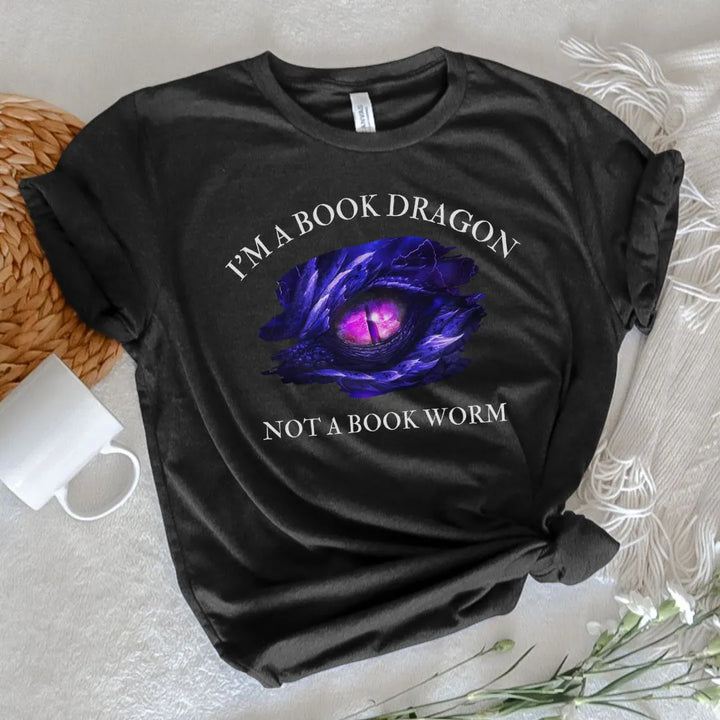 A short sleeve heather black t-shirt. Design on the shirt reads "I'm a book dragon not a book worm." Between the text is the purple dragon eye from the cover of Stormsight.