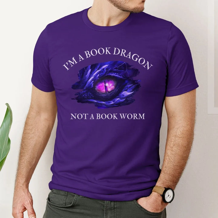 A man wearing a short sleeve purple t-shirt. Design on the shirt reads "I'm a book dragon not a book worm." Between the text is the purple dragon eye from the cover of Stormsight.