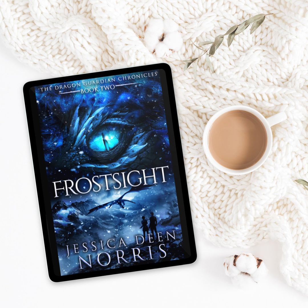 Frostsight ebook with cover showing on a tablet device. Cover features the title across the middle with a blue dragon eye and "The Dragon Guardian Chronicles Book 2" above it. Below the title, the two main characters watch a dragon in the distance in a snowy mountain landscape. The author's name is at the bottom of the cover.