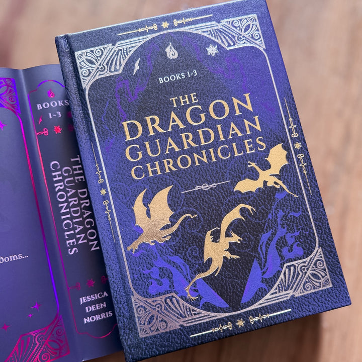 Book titled 'The Dragon Guardian Chronicles' with dragon illustrations on a wooden surface