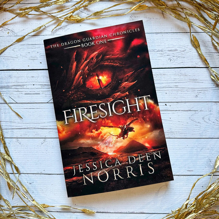 Firesight paperback cover. Cover features the title across the middle with a red dragon eye and "The Dragon Guardian Chronicles Book 1" above it. Below the title, the two main characters ride on a dragon over a volcano erupting. The author's name is at the bottom of the cover.#autograph-option_signed-by-author