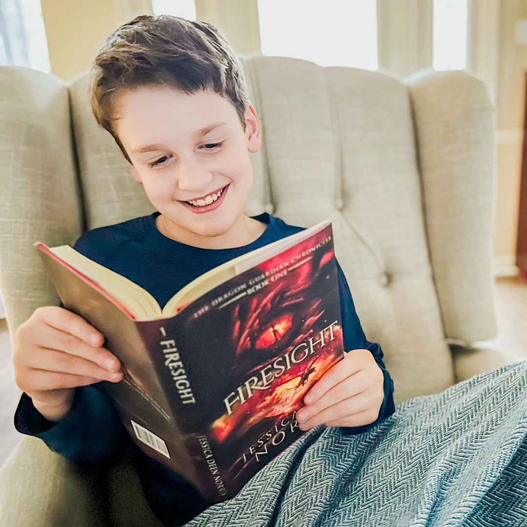 A young boy smiling and reading a copy of Firesight