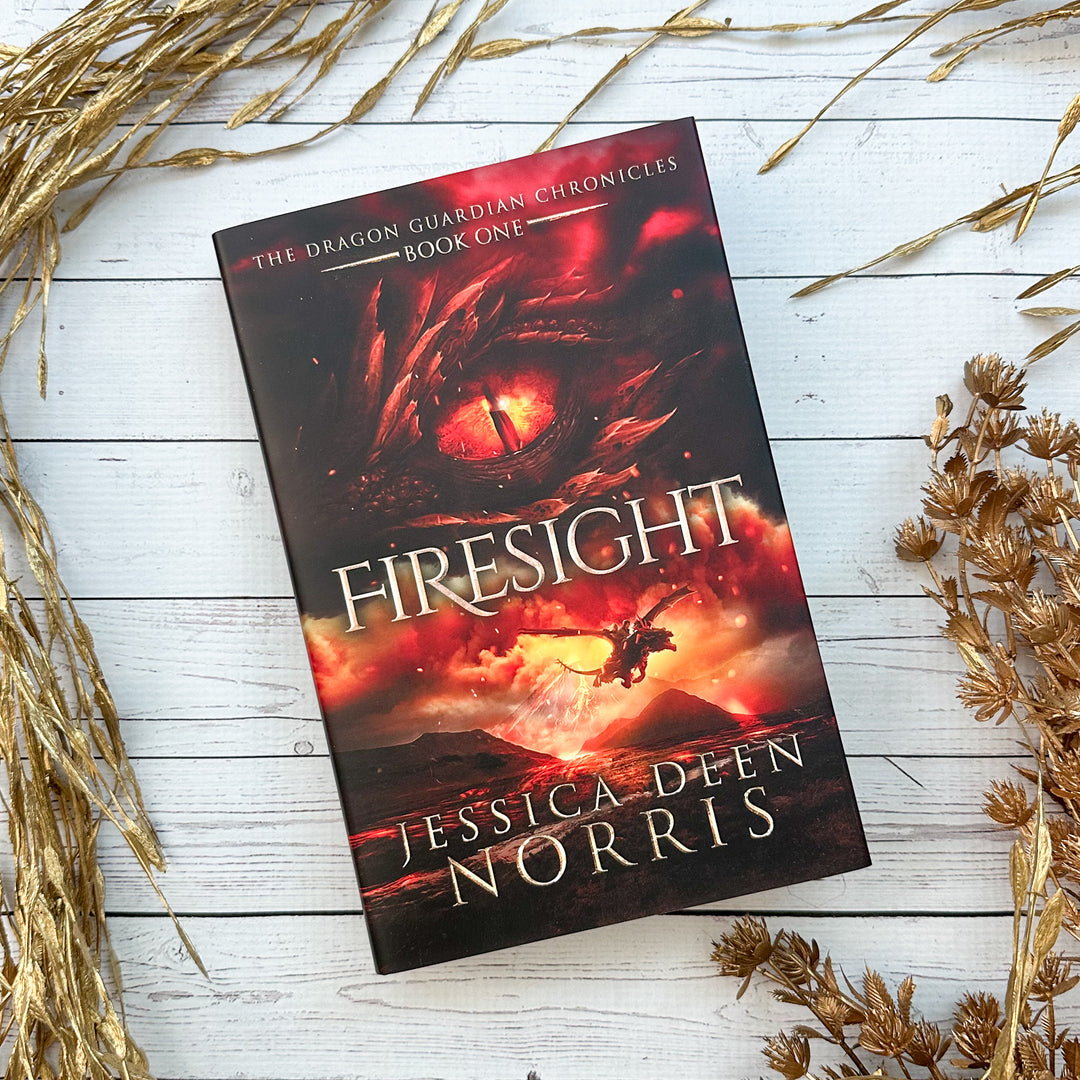 Firesight hardcover cover. Cover features the title across the middle with a red dragon eye and "The Dragon Guardian Chronicles Book 1" above it. Below the title, the two main characters ride on a dragon over a volcano erupting. The author's name is at the bottom of the cover.#autograph-option_signed-by-author
