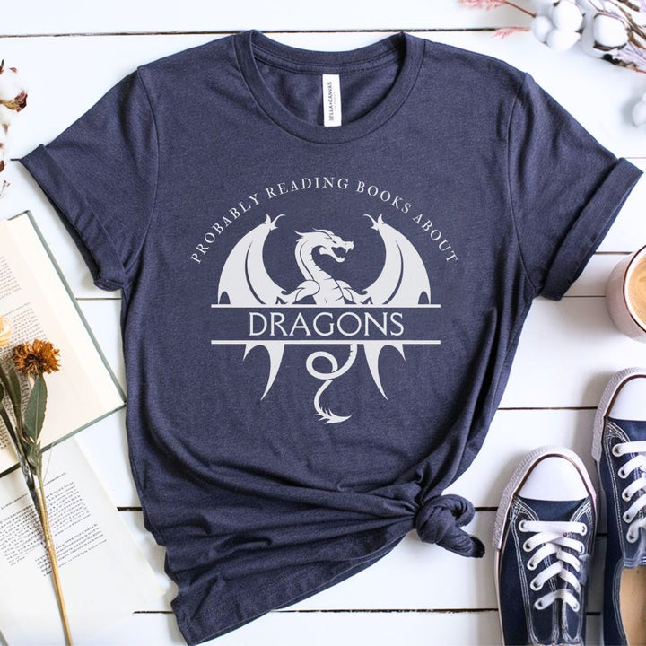 A short sleeve heather navy t-shirt. The white design on the shirt reads "Probably reading books about dragons." The word "dragons" is set apart on top of a large dragon.