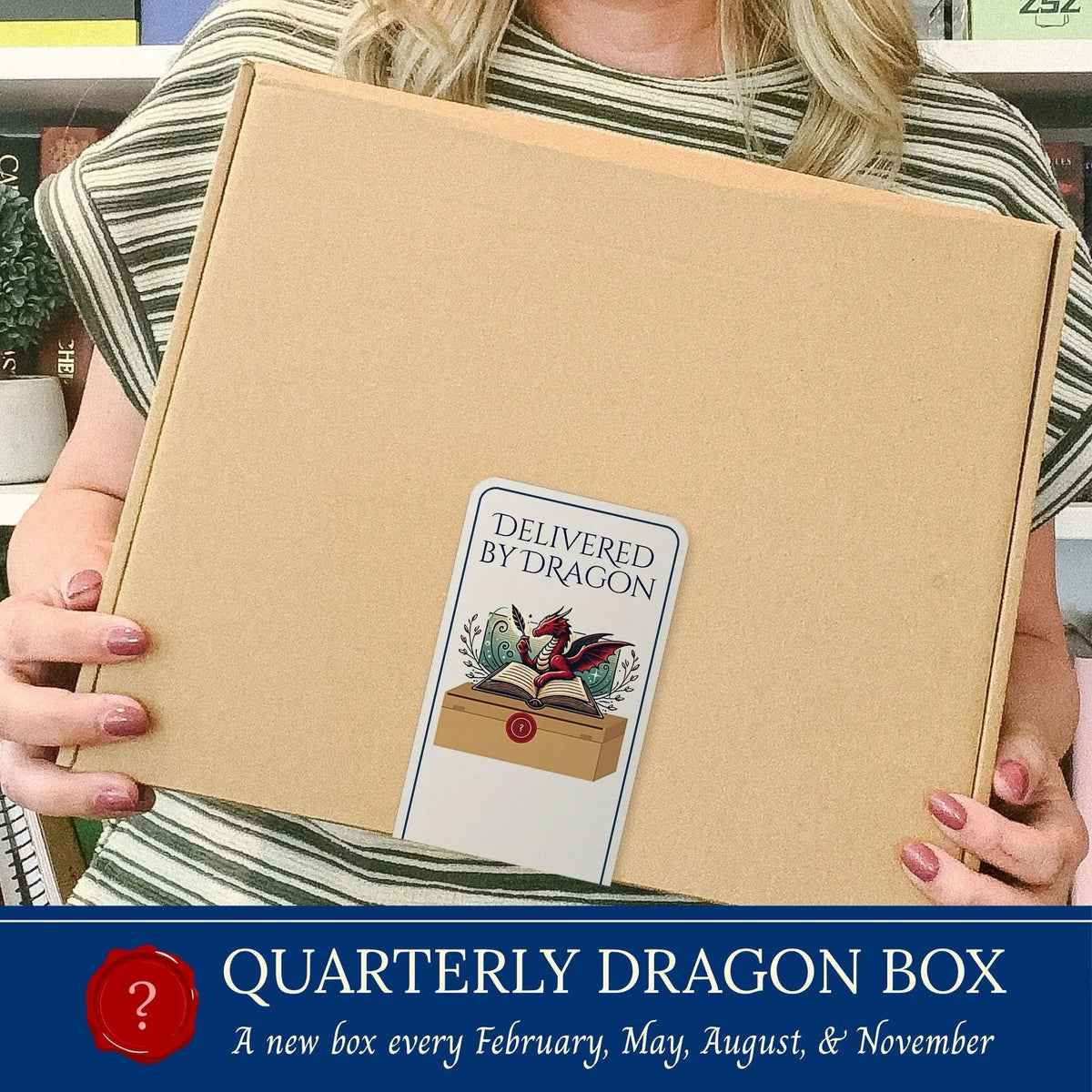 A person holds a large brown cardboard box labeled 'Delivered by Dragon' in a real indoor setting. The box has a decorative dragon illustration and the text 'QUARTERLY DRAGON BOX' and 'A new box every February, May, August, and November' appears in a dark blue banner at the bottom of the image.