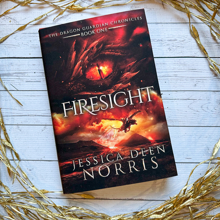 Firesight hardcover cover. Cover features the title across the middle with a red dragon eye and "The Dragon Guardian Chronicles Book 1" above it. Below the title, the two main characters ride on a dragon over a volcano erupting. The author's name is at the bottom of the cover.
